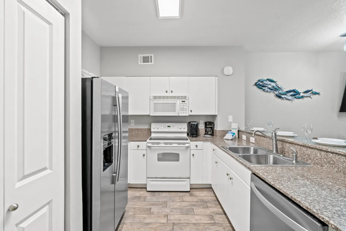 A modern kitchen area featuring stainless steel appliances, granite countertops, white cabinetry, and decorative wall art. This inviting space is ready for meal preparation, family gatherings, and shared moments, reflecting the high standards of convenience and functionality promised to guests.