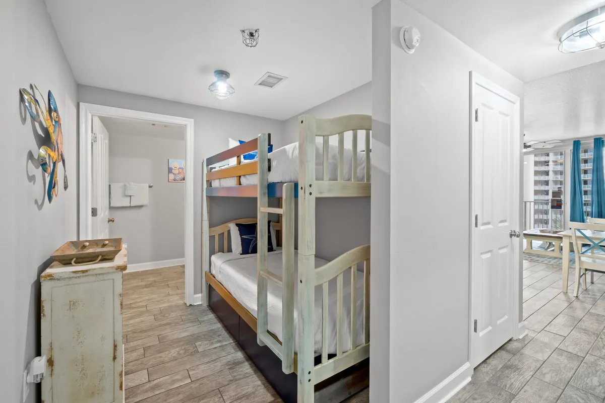 A practical, family-friendly bunk nook with twin-sized bunk beds, a bathroom entrance nearby, and a hallway leading to the main living area. The space is simple, welcoming, and ideal for kids or extra guests.