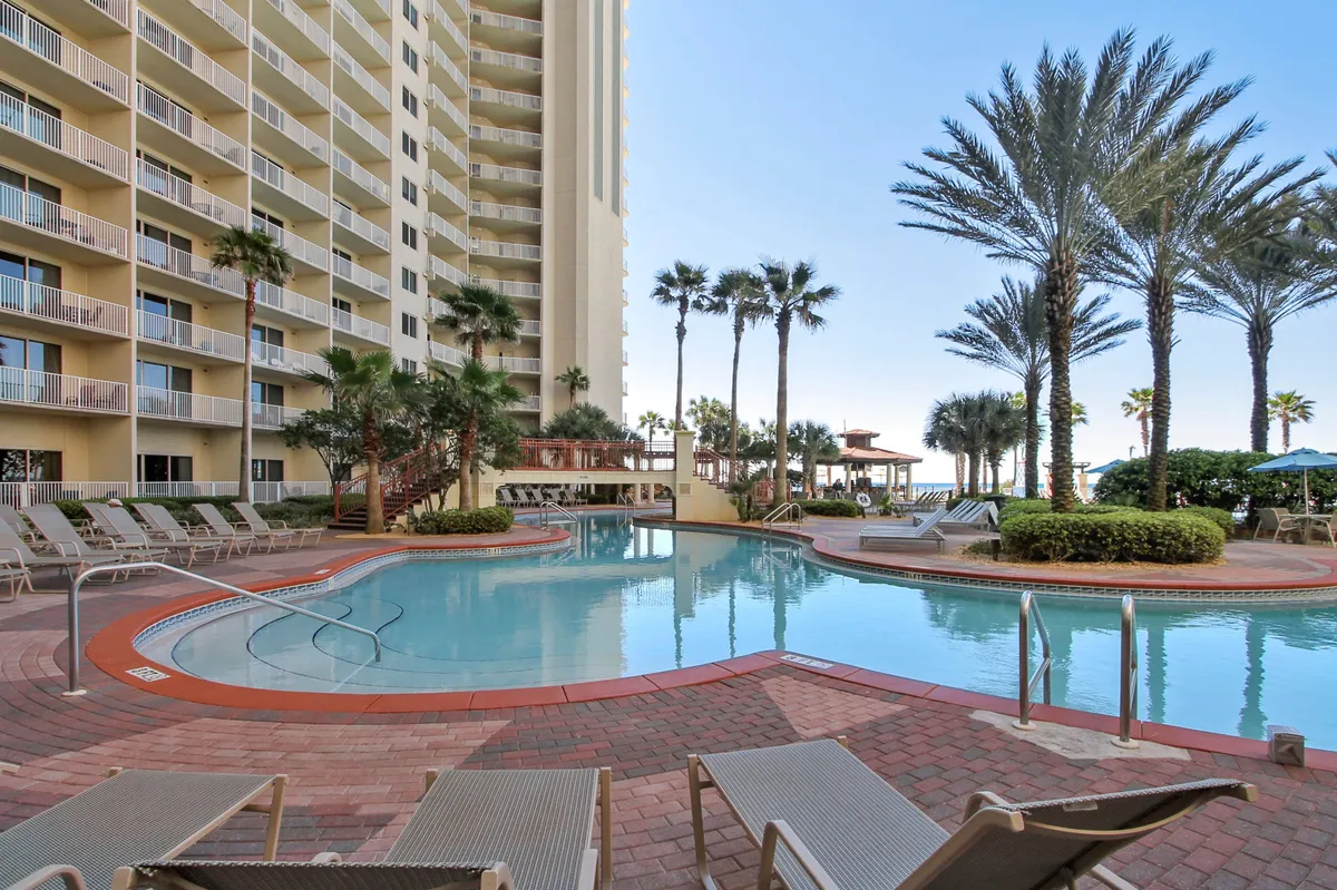 This exterior shot captures the resort’s signature curved lagoon-style swimming pool surrounded by tall palm trees and the high-rise Shores of Panama building. Lounge chairs line the pool, and the scene glows with a leisurely, vacation-ready energy. The pool’s size and inviting waters make it perfect for family fun and relaxation, directly referencing the section’s mention of starting the day by splashing in the resort pool.
