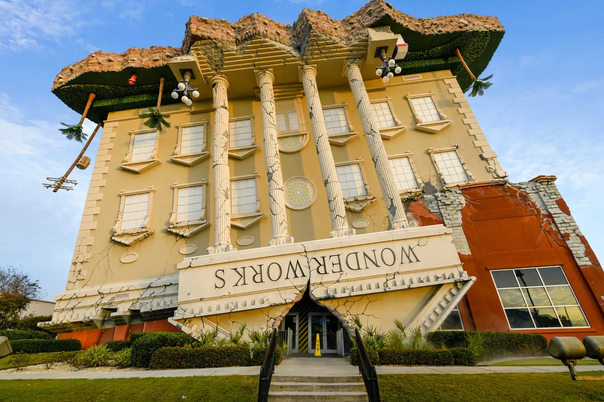 A playful, eye-catching shot of the upside-down WonderWorks building, featuring classical columns and bold signage. The unique architecture stands out against the blue sky, inviting curiosity and fun.