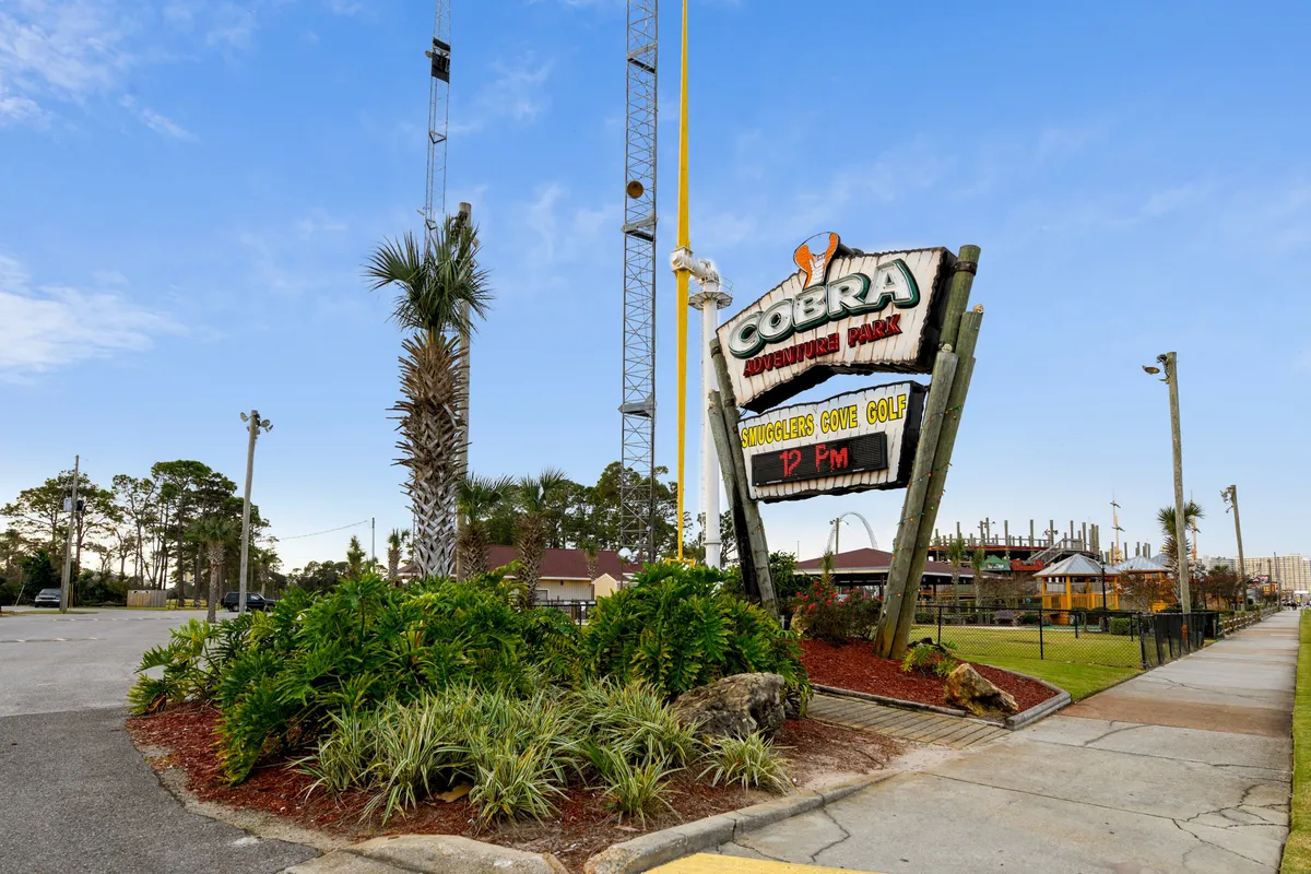 Cobra Adventure Park is showcased with a vibrant mini golf course, tall amusement rides, and lush greenery. The sign and energetic atmosphere signal a place for shared family fun, games, and outdoor play—ideal for both summer and cooler months.